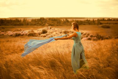 Geri, uçan mavi kumaşlı kızın dikiz aynası. Açık hava çekimi. Genç bir kadın uzun ve zarif bir elbise giyer. Rüya gören dişiler çim tarlalarına, yaz ormanlarına ve gökyüzüne karşı rüzgarlı havanın keyfini çıkarırlar.