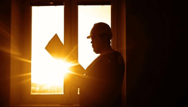 Güvenlik kaskı takan mühendis planlara bakıyor.