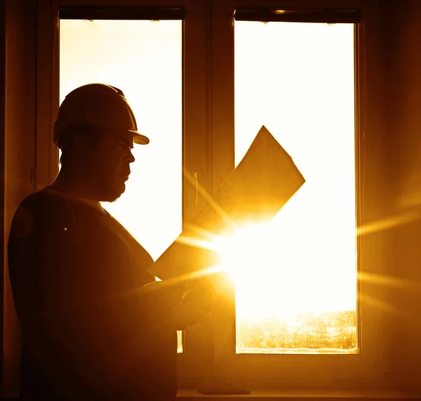 male builder engineer wearing  security helmet looking  at blueprint