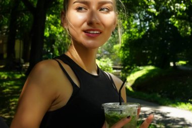 Güzel sarışın kız elinde şeffaf plastik bardakla mojito kokteyli tutuyor. Aynanın yanında duran kadın 