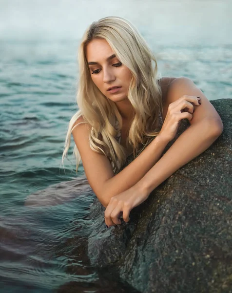 Young blonde woman wearing  white bikini. sunset beach.