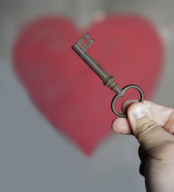 Erkek el, duvarın arkasında kırmızı kalpli eski bir anahtar tutuyor..