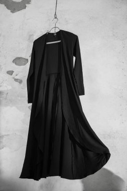 Duvardan izole edilmiş metal elbise askılığı üzerinde şık uzun bir elbise..