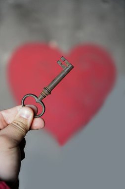 Erkek el, duvarın arkasında kırmızı kalpli eski bir anahtar tutuyor..