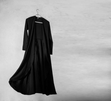 Duvardan izole edilmiş metal elbise askılığı üzerinde şık uzun bir elbise..