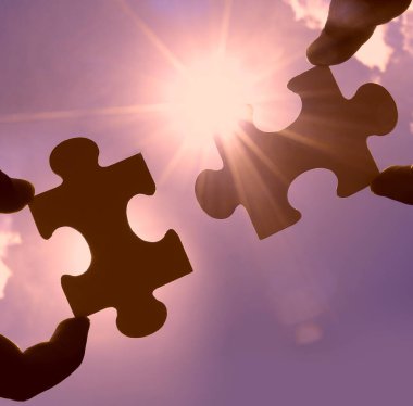 Gökyüzü arka planında yapboz parçaları olan eller.  