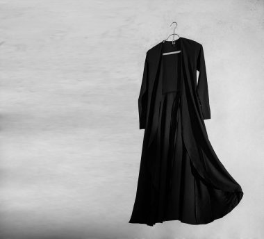 Duvardan izole edilmiş metal elbise askılığı üzerinde şık uzun bir elbise..