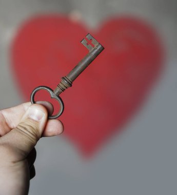 Erkek el, duvarın arkasında kırmızı kalpli eski bir anahtar tutuyor..