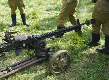 Ağır makineli tüfek. Eski güçlü askeri makineli tüfek. Uzun namlulu. Asker ayakta duruyor..