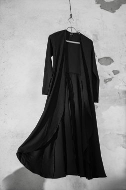 Duvardan izole edilmiş metal elbise askılığı üzerinde şık uzun bir elbise..