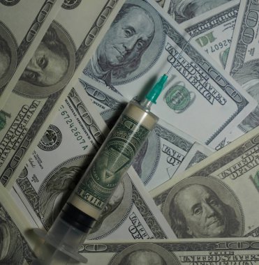 İçinde 100 dolarlık banknotların olduğu bir şırınga. Her şeyi gören gözü olan bir piramit.