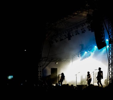 Rock konserindeki bir sürü insan. Müzikal bir rock festivalinde sahne alan bir vokalist ve gitarist silueti. Konserdeki izleyiciler. Müzisyenlerin konser fotoğrafı. rock grubu. 