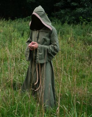 Yeşil kefeni olan tanınmayan bir cadı. Erkek sihirbaz, arka planda yeşil alanda duruyor..