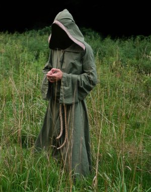 Yeşil kefeni olan tanınmayan bir cadı. Erkek sihirbaz, arka planda yeşil alanda duruyor..