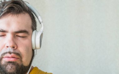 Yakışıklı esmer hippi adamın portresi. Gözleri kapalı ve siyah bıyıklı. Gri desenli arka planda sakin müzik dinliyor. İyi bir şey hayal et. 