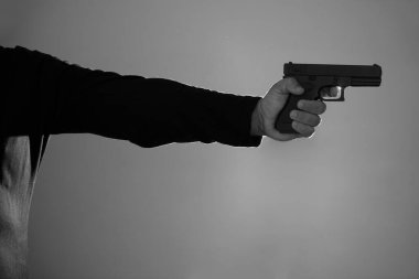 Erkek eli silah tutuyor. Siyah tabanca silueti. Parmağını tetiğe koy.