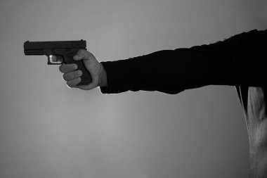 Erkek eli silah tutuyor. Siyah tabanca silueti. Parmağını tetiğe koy.
