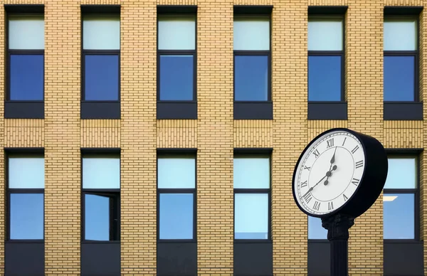 Clock of office building. Modern round clock in the background of brick building. time is money idea.