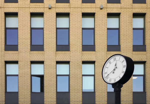 Clock of office building. Modern round clock in the background of brick building. time is money idea.