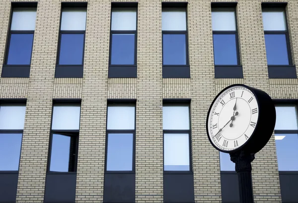 Clock of office building. Modern round clock in the background of brick building. time is money idea.