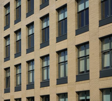 Pencereli sarı tuğlalı bir binanın ön cephesi. Modern ofis binası cephesi 