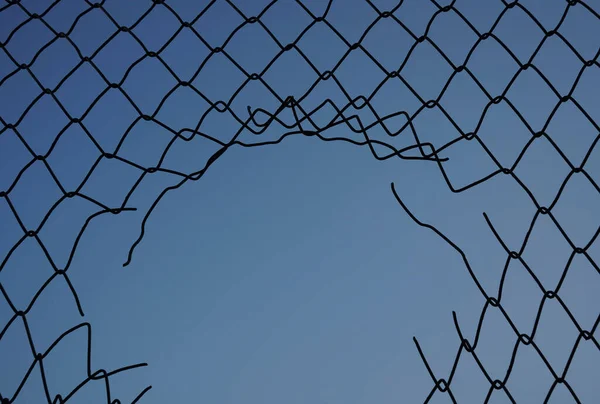 damage wire mesh on blue sky  background. Mesh netting with hole isolated on blue  background