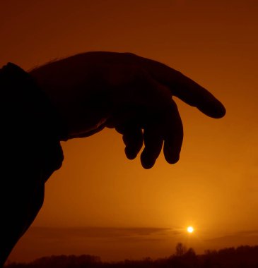 Bulanık arkaplanda bir insan elinin silüeti.