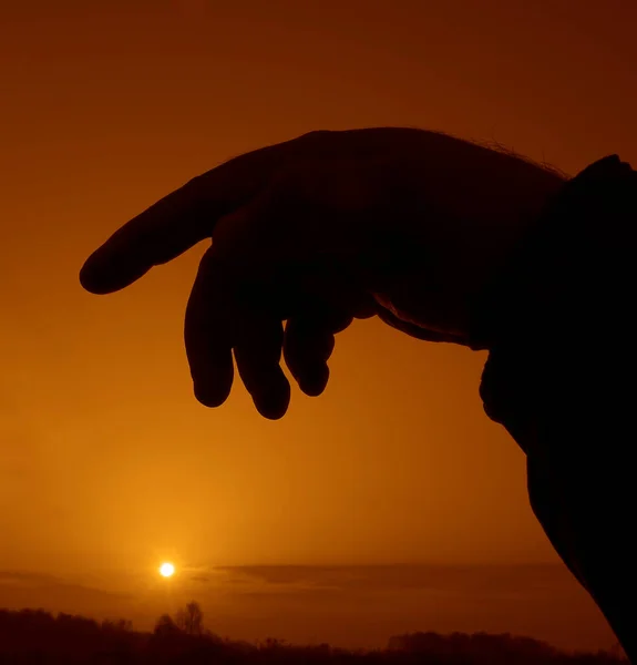 A silhouette of a human hand on blurred  landscape background