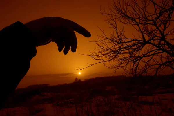 A silhouette of a human hand on blurred  landscape background