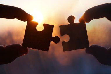 Gökyüzü arka planında yapboz parçaları olan eller.  