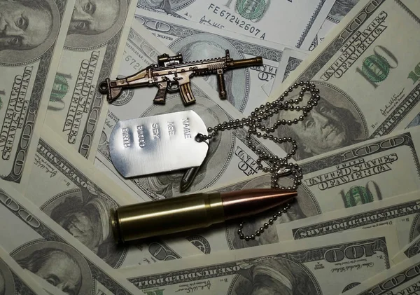 The medallion of a military soldier lies on dollar bills. Concept: price of a military operation, military mercenaries, army pension for the military.