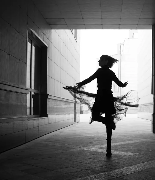 woman dances to the music in the city. silhouette of girl dancing between walls.