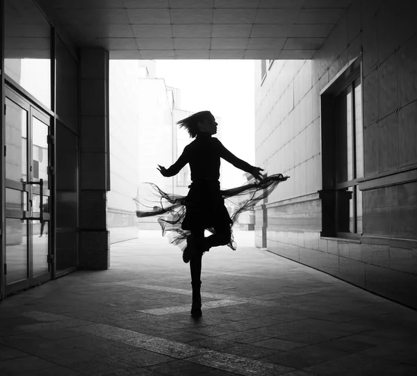 woman dances to the music in the city. silhouette of girl dancing between walls.