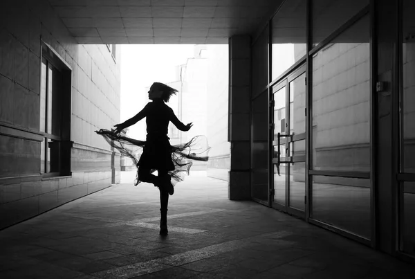 woman dances to the music in the city. silhouette of girl dancing between walls.