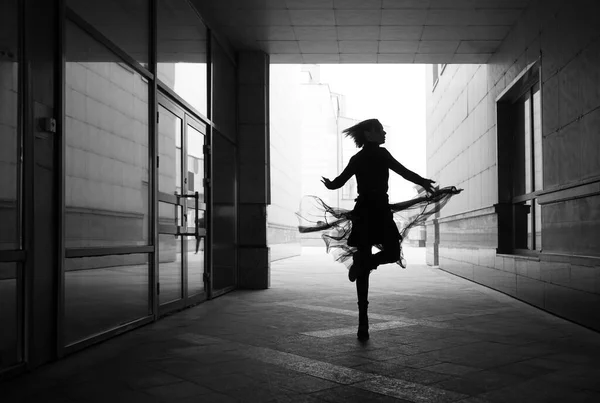 woman dances to the music in the city. silhouette of girl dancing between walls.