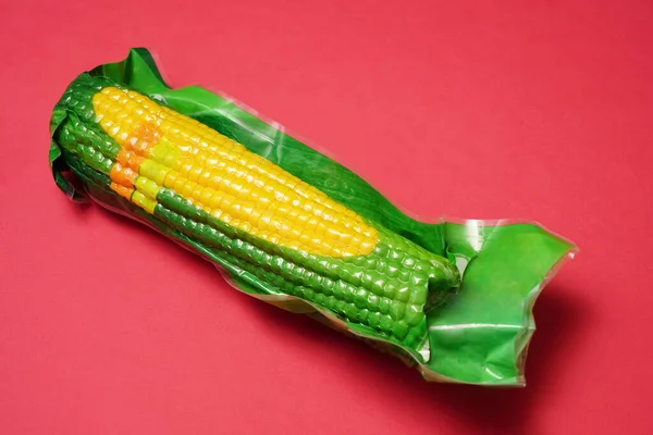 Одна Кукуруза Кукурузы Початке Пластиковой Вакуумной Упаковке Изолированы Красном Фоне — стоковое фото
