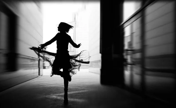 woman dances to the music in the city. silhouette of girl dancing between walls.