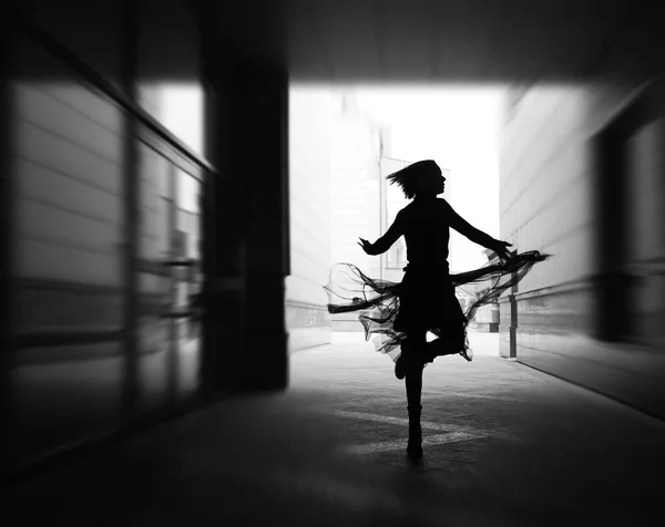 woman dances to the music in the city. silhouette of girl dancing between walls.