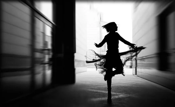 woman dances to the music in the city. silhouette of girl dancing between walls.