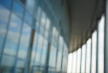 Binanın arka planındaki bulanık mavi cam duvar. Ofisin arka planındaki bulanık ofis lobisi. İç mekan boş. Cam duvardan gelen bulanık ışık var. 