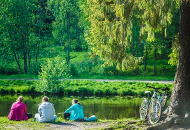Yaz parkında üç genç kadın dinleniyor.