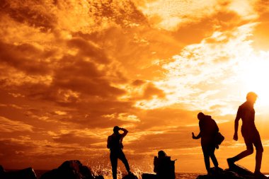 Turistlerin silueti fotoğraf çekiyor. Cep telefonu kullanan genç bir kadının yan görüntüsü. Denizin fotoğraflarını çek.