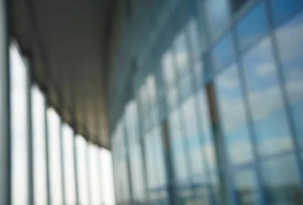 Blurred abstract blue glass wall from building background. Business building blur background office lobby hall interior empty indoor room with blurry light from glass wall