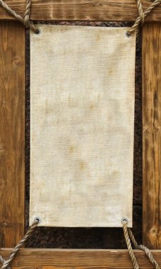 İp ve halat çerçevelerinde asılı tahta tabela. Arkaplanda taş duvar