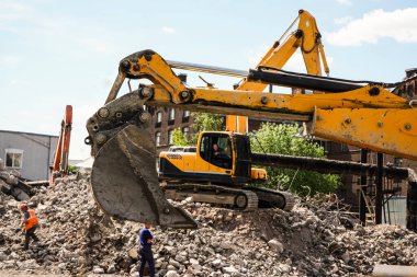 Sarı kazıcı, yıkım sonrası çöp ve döküntü kamyonu yüklüyor.