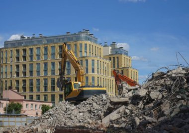 Turuncu kazıcı, yıkımdan sonra bir çöp kamyonunu enkaz ve çöplerle dolduruyor.