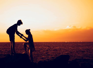 Adam, gün ışığında kadının dağa tırmanmasına yardım ediyor. Yardım eli uzatıyorum. Tırmanıyorum. Konsepte yardımcı oluyor. Birbirine aşık çift