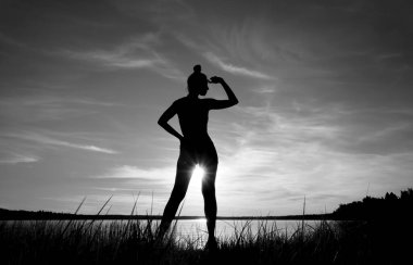 Kısa elbiseli, ayakta duran ve arka planda güneşlenen kız silueti. deniz manzarası.