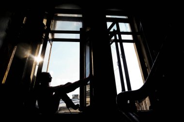 Pencere pervazında oturan rüya gören kadın silueti. Saint Petersburg 'daki eski giriş.