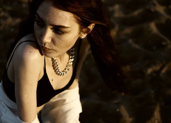 夕日のビーチを背景に砂の上で考えて白いシャツを着た赤毛の官能的な女の子 夏の季節 — ストック写真